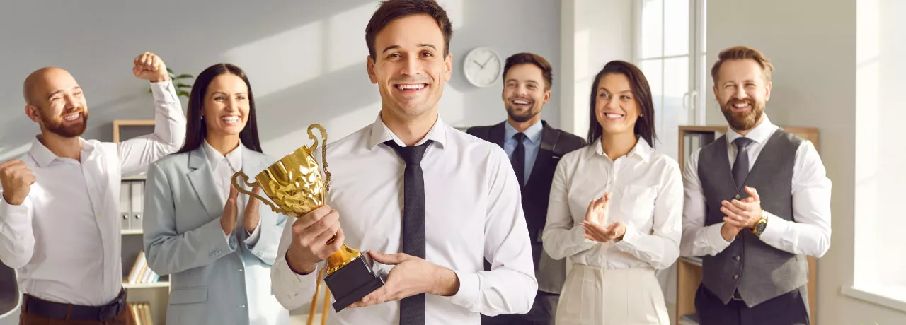 An employee holding an award trophy in front of their colleagues