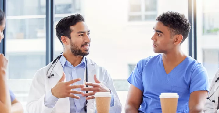 Two doctors and two nurses chatting at a table with coffee