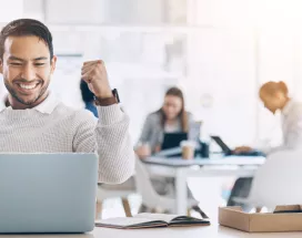 Image shows an employee celebrating by their computer.