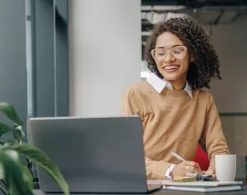 Employee smiling as they communicate at work on their laptop