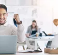 Image shows an employee celebrating by their computer.