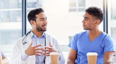 Two doctors and two nurses chatting at a table with coffee