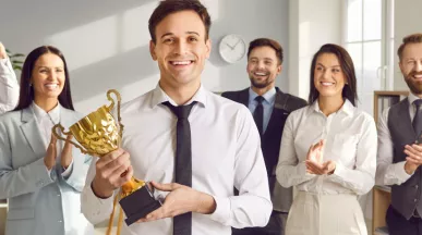 An employee holding an award trophy in front of their colleagues