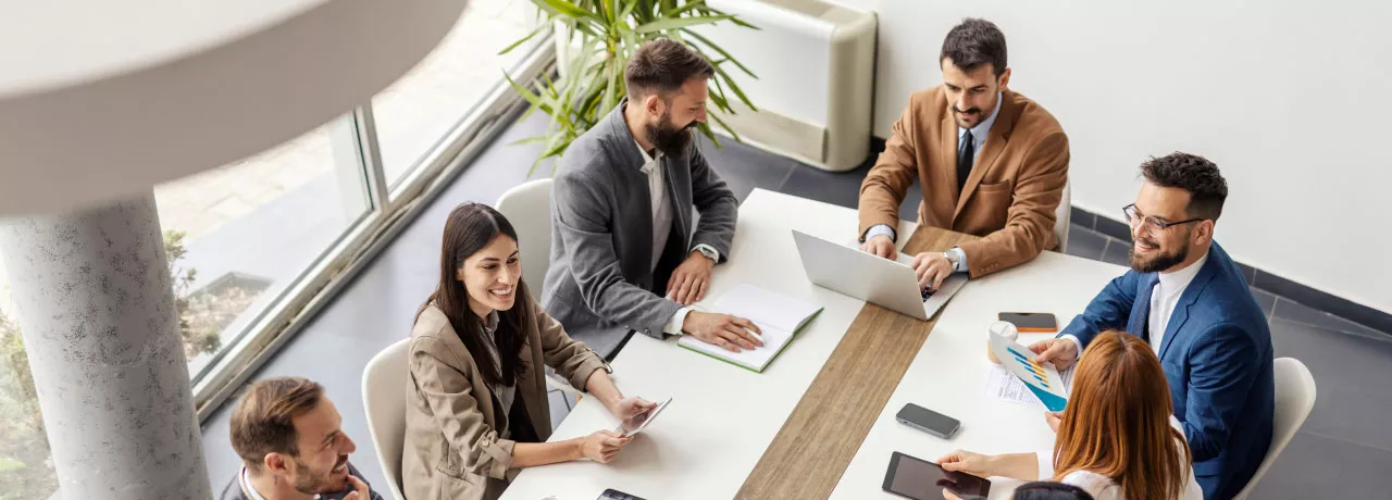 An image of a leadership team going over ways to create a healthy company culture and positive work culture to recognize employees and contribute to business success. They are discussing team building activities to integrate new employees into the organization's culture to create a positive environment and overall thriving culture.