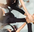 A group of employees huddled together with their hands stacked together.