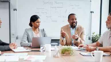 Coworkers sitting around a table with the focus on a one employee in the middle