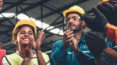 A photograph of construction workers clapping in a circle