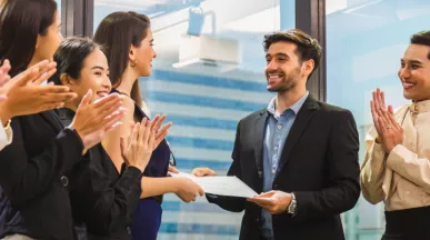 Image shows an employee receiving a certificate in front of a group of employees.