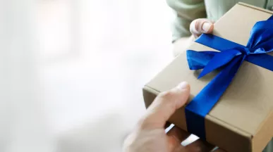 Image shows a person handing a gift to another person