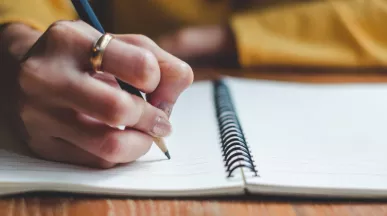 Image shows a close up of a person writing a message