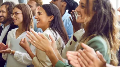 Image shows multiple employees clapping and smiling in the same direction.