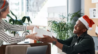 An employee giving their co-worker a holiday gift for appreciation