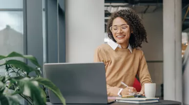 Employee smiling as they communicate at work on their laptop