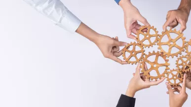 A group of employees creating a cogwheel with each holding a small cog